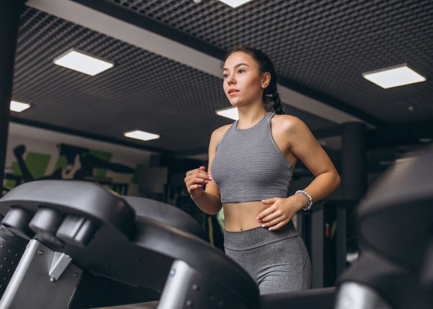 девушка бегает на беговой дорожке в спортивном зале